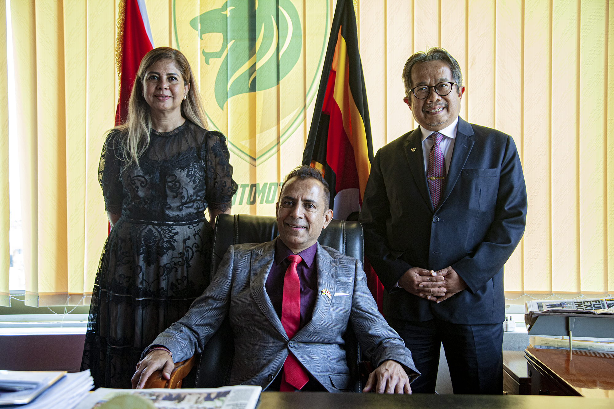 Mr. Paresh Shukla with guests beneath the Simba Automotives and Uganda flag