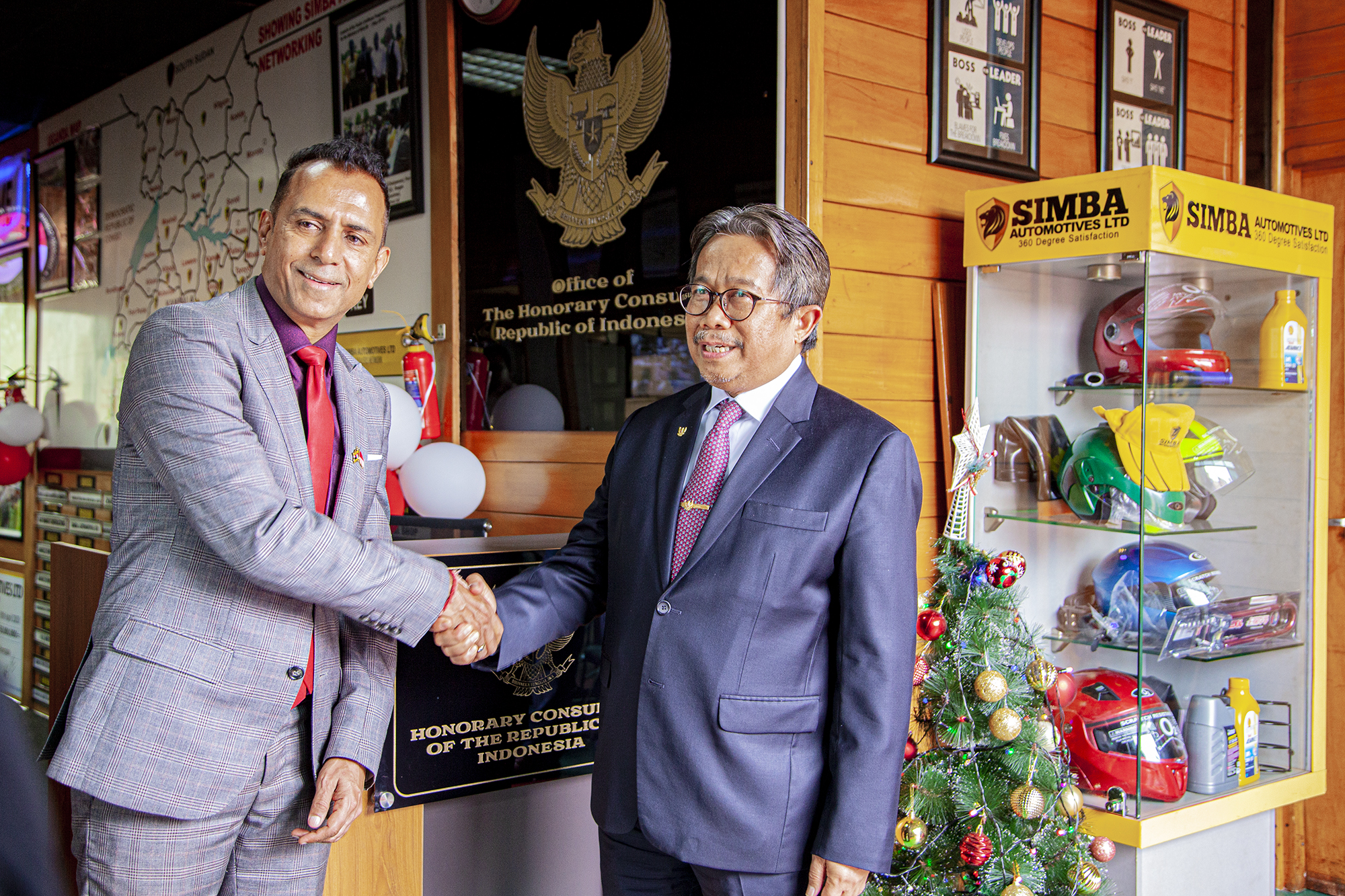 Mr. Paresh Shukla shaking hands beneath the Office of the Honorary Consulate sign